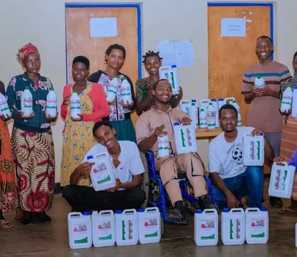 Young farmers smiling and holding containers of HINGA WEZE
