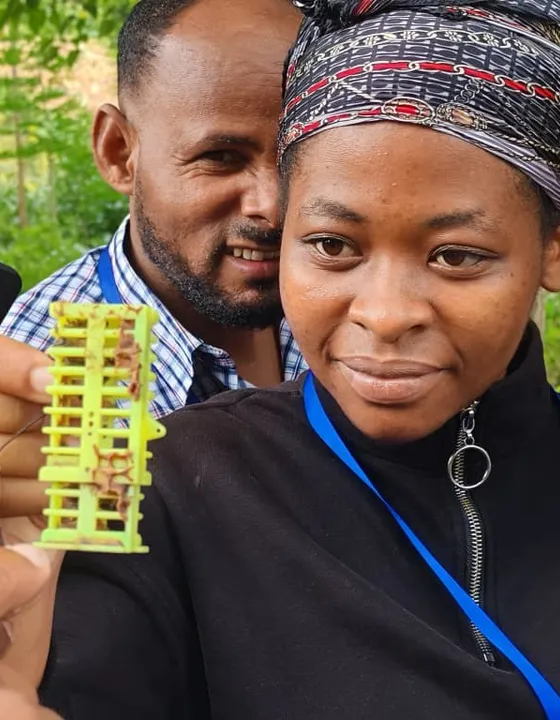 A participant holding a beekeeping tool used for raising queen bees