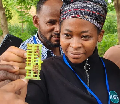 A participant holding a beekeeping tool used for raising queen bees