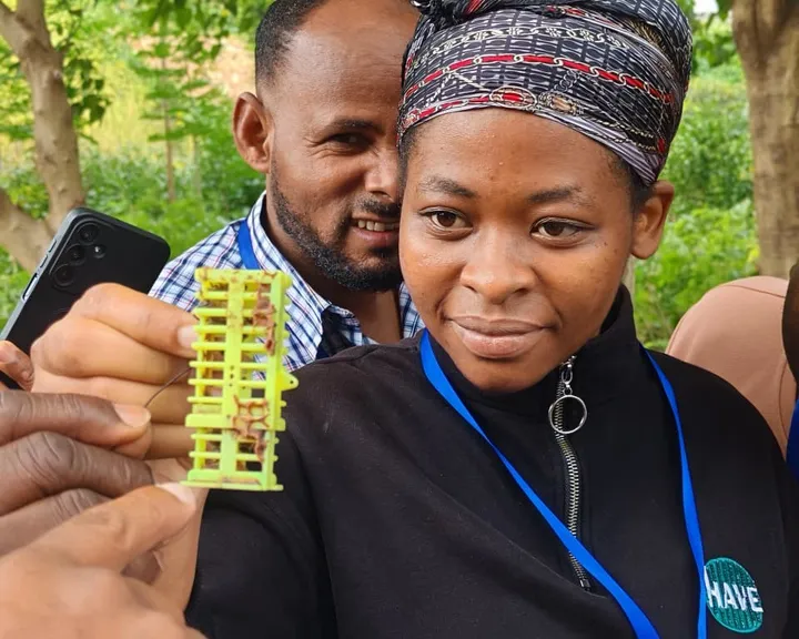 A participant holding a beekeeping tool used for raising queen bees